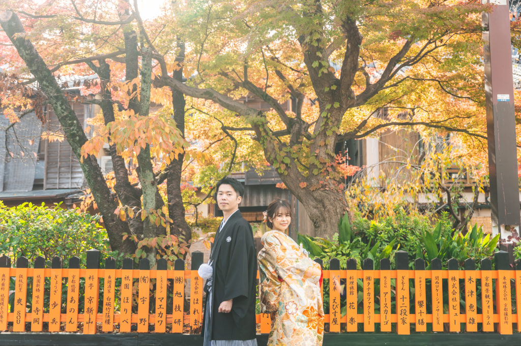 京都の祇園の紅葉を背景に背中合わせの和装前撮り